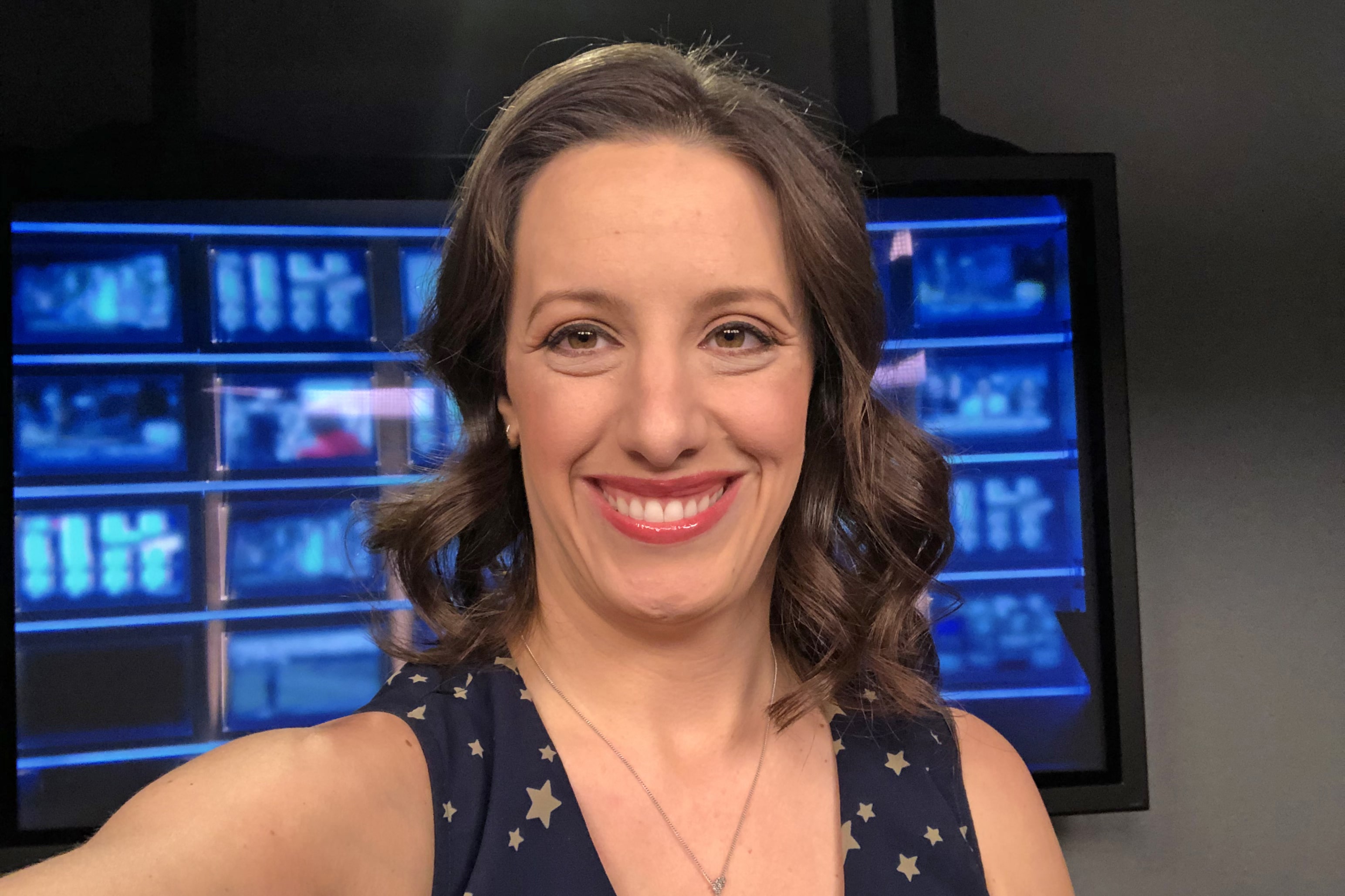 Laura Forczyk taking a selfie in front of screens depicting various graphs, data and information, representing her expertise in space industry career coaching and courses